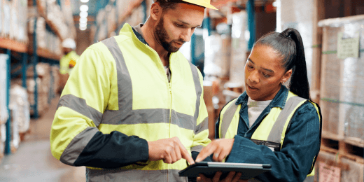 Two workers in a warehouse holding a tablet